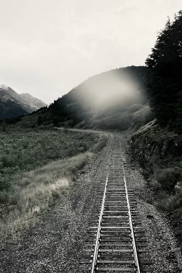 One set of train tracks heading straight forward then curving left.