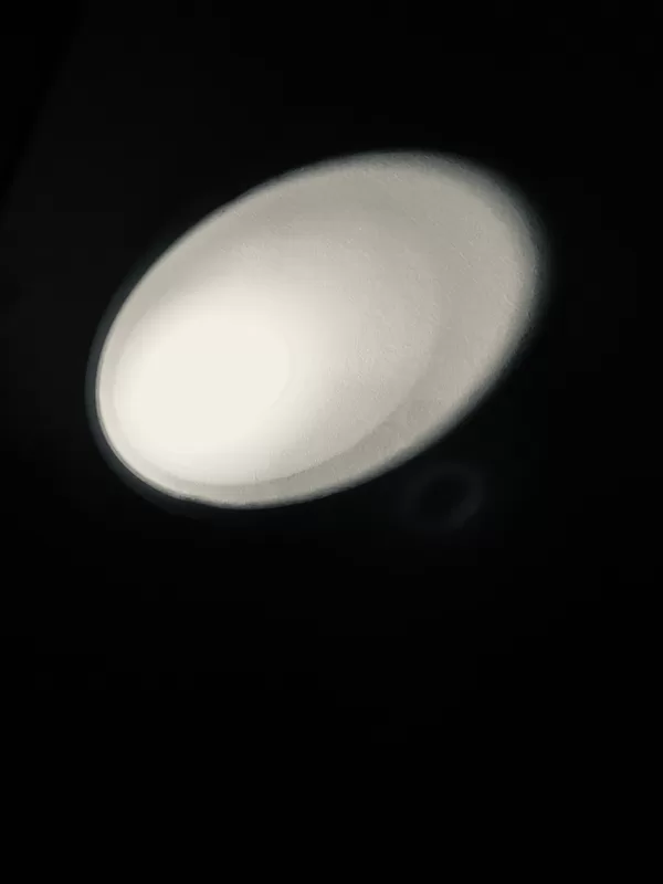 Flashlight beam on a wall in the shape of an ellipse.